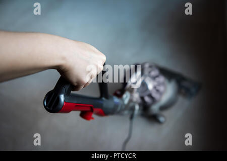 Nahaufnahme, hohen Winkel, Oben, Unten Blick einer Hand, die den Griff des Staubsaugers Reinigung Zimmer Teppichboden Stockfoto