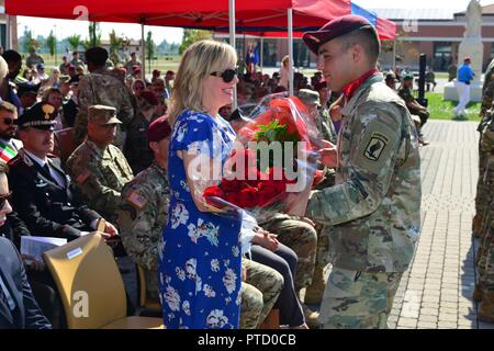 Ehefrau von Oberst Gregory Anderson, ausgehende Kommandant der 173Rd Airborne Brigade, erhält ein Bouquet von roten Blumen aus ein Fallschirmjäger bei der Änderung von Befehl Zeremonie an Caserma Del Din in Vicenza, Italien, 7. Juli 2017. Die 173Rd Airborne Brigade, in Vicenza, Italien, ist die Armee Contingency Response Force in Europa, und ist in der Lage, Kräfte projizieren, das volle Spektrum militärischer Operationen in den Vereinigten Staaten der Europäischen, Zentralen und Verantwortungsbereiche afrikanischen Befehle durchzuführen. Stockfoto