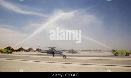 Us Marine Corps Maj. Jasmin Moghbeli, ein Pilotprojekt zu Marine Test und Bewertung Squadron (VMX) 1, steht Ihr AH-1 Cobra' als Marines Marine Corps Air Station Yuma, Ariz., Flugzeuge Rettung und Brandbekämpfung (ARFF) Spray und Arch von Wasser als Teil eines traditionellen 'Wet' Juli 7, 2017 zugewiesen. Maj. Moghbeli Berichten dem Johnson Space Center in Houston, Texas, später in diesem Jahr der NASA-Astronaut Kandidat Klasse von 2017 zu besuchen. Stockfoto