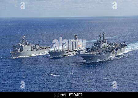 CORAL SEA (10 Juli 2017) Die Amphibious Assault ship USS BONHOMME RICHARD (LHD 6) parow Neben der Henry J. Kaiser-Klasse Flotte Auffüllung öler USNS John Ericsson (T-AO 194) und das Dock Landung Schiff USS Ashland (LSD 48) zur Auffüllung auf See während der Talisman Säbel. Bonhomme Richard, Teil einer kombinierten US-Australia-New Zealand Expeditionary strike Group, durchläuft eine Reihe von Szenarien, die Naval Fertigkeiten werden im Betrieb gegen den blauen erhöhen - Wasser kontradiktorischen Bedrohungen und in seiner primären Aufgabe der Einleitung Marine an Land in der littorals. Talisman Sabre ist ein Bien Stockfoto