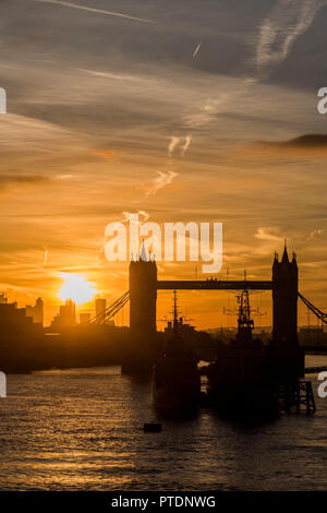 London, Großbritannien. 9. Okt. 2018. Die Sonne geht ofer Tower Bridge und HMS Belfast als Menschen pendeln in die Arbeit über London Bridge. Credit: Guy Bell/Alamy leben Nachrichten Stockfoto