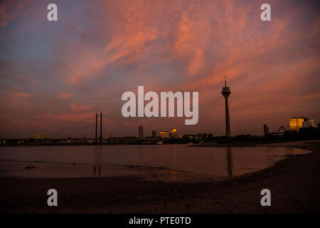 09 Oktober 2018, Nordrhein-Westfalen, Düsseldorf: Der Himmel rötlich ist bei Sonnenuntergang hinter der Rheinkniebrücke (l) und der Rheinturm. Foto: Christophe Kirschtorte/dpa Stockfoto