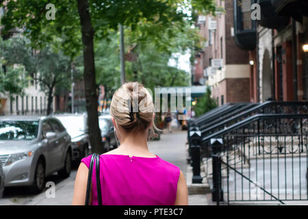 Zurück auf Frau zu Fuß in New York City Bürgersteig Straße mit braunen Steinen Stockfoto