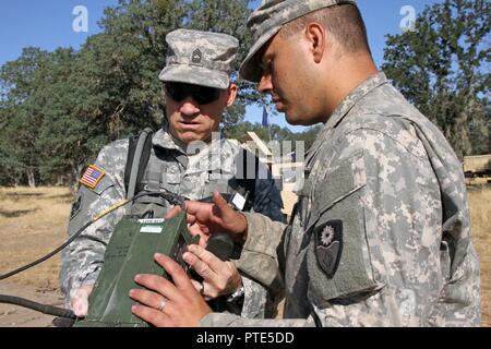 Spc. Dean Stubblefield, Recht, ein Signal support systems Specialist mit den 149 chemischen, biologischen, radiologischen, nuklearen (CBRN) Unternehmen, 49th Military Police Brigade, Oklahoma Army National Guard, erklärt radio Betrieb seines Unternehmens führen Beobachter Controller/Trainer (OC/T) und die US-amerikanische Armee-reservesoldat, Master Sgt. Michael Nö der 91st Training Division, 84th Ausbildung Befehl, während eines Combat Support Training (CSTX) am Fort Hunter Liggett, Calif., 12. Juli 2017. OC/T's sind die Überwachung der fast 5.400 Service Mitglieder aus der US-Army, US-Army, Army National Guard Stockfoto