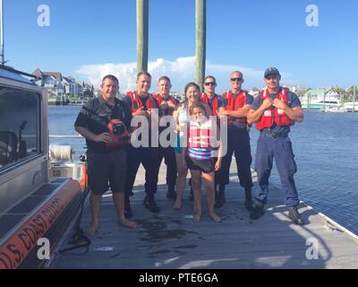 Ein Coast Guard Antwort Boat-Small Crew von Station Oak Island steht mit Überlebenden nach einer wasserrettung am 15. Juli 2017, in der Nähe der kleine Knaben Strand in Oak Island, North Carolina. Küstenwache sind von links nach rechts Petty Officer 3. Klasse Holden Grün, Feuerwehrmann Jesse Piloto, Petty Officer 2nd class Derek Brandon, Petty Officer 3. Klasse David Youngs und Seaman Mazen Louden. Stockfoto