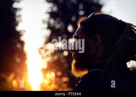 Mann Silhouette mit Dreadlocks in Sunset Mountain Forest Stockfoto