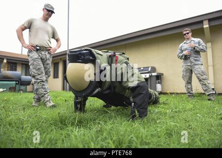 Us Air Force Academy Cadet 2. Klasse Harry McMahon führt einen Push up in eine Beseitigung von Explosivstoffen Anzug bei Kunsan Air Base, die Republik Korea, 11. Juli 2017 während der US Air Force E.O.D. Mitglieder beobachten ihn während der kadetten besuchen. Der Besuch war Teil der Operation Air Force Programm der Air Force Academy. Betrieb Luftwaffe nimmt steigende Jüngere in der Air Force Academy zu verschiedenen Basen in der Luftwaffe zu Schatten und über die Mission in den verschiedenen Basen lernen. Stockfoto