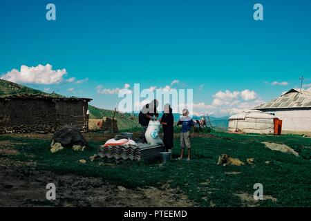 Sicherheit und Gesundheitsschutz bei der Arbeit/Kirgisistan - 21. MAI 2011: Familie Vorbereiten von Korn für das Huhn neben ihrer Jurte hoch oben in den Bergen von Alai Bereich Stockfoto