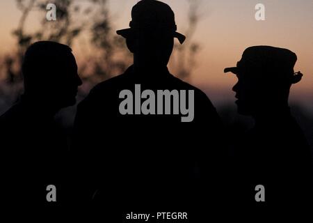 Marines mit Waffen Firma, Bataillon Landung Team, 3rd Battalion, 5th Marines, verbringen Sie ein paar Minuten Pause, als die Sonne am Ende des Tages fünf der Übung Talisman Sabre 17 auf Townshend Insel, Shoalwater Bay, Queensland, Australien, 17. Juli 2017 setzt. BLT 3/5, die Bodenkampf Element für die 31 Marine Expeditionary Unit, ist die Erkundung state-of-the-Art Konzepte und Technologien wie die engagierte Kraft für Sea Dragon2025, eine Marine Corps Initiative für die zukünftigen Kämpfe vorzubereiten. Die 31. MEU beteiligt sich an Talisman Sabre 17 während auf eine regelmäßig geplante Patrouille der bereitgestellten Stockfoto