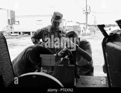 Spc. Corbin Schick und SPC. Brian Bui, sowohl von Unternehmen D, 2.BATAILLON, 151 Infanterie Regiment, 76th Infantry Brigade Combat Team, 38th Infantry Division, Indiana Army National Guard, installiert eine Laser Sendeanlage auf dem M4 Carbine für Sgt. 1. Klasse Jose Rosario, von C Firma, 1 Battalion, 65th Infantry Regiment, Puerto Rico Army National Guard, auf Forward Operating Base Krieger an das Joint Readiness Training Center in Fort Polk, Louisiana, Dienstag, 18. Juli 2017. Der laser Sender ermöglichen die Waffen Hits auf gegensätzlichen Kräfte während Wargames bei JRTC zu simulieren. Stockfoto