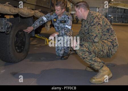 CORAL SEA (20. Juli 2017) der Australischen Armee Sgt. Julian Evans (links) und die US-amerikanische Marine Staff Sgt. Alfonso Garcia, zugeordnet zu den 31 Marine Expeditionary Unit (MEU) und begann mit dem Amphibisches Schiff USS BONHOMME RICHARD (LHD6), diskutieren die Möglichkeiten der Australischen Armee Leichte gepanzerte Fahrzeuge (LAV) auf dem Hangardeck der Royal Australian Navy Amphibious Assault ship HMAS Canberra (III) (L02) während einer Schiffstour. Der Besuch war Teil eines Personalaustausch zwischen den beiden amphibische Schiffe gemacht für die Mitglieder der beiden Schiffe eine Gelegenheit, über die Professional zu erfahren Stockfoto