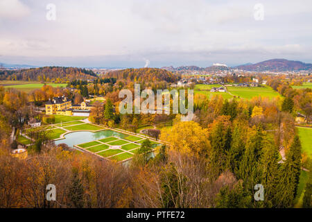 Panoramablick auf das Schloss Hellbrunn (Schloss Hellbrunn) und Park an einem schönen Herbsttag. Die Festung Hohensalzburg auf dem Hintergrund gesehen. Salzburg, Österreich. Stockfoto