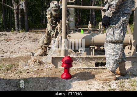 U.S. Army Reserve Soldaten mit der 728Th Quartermaster Unternehmen, Fremont, Neb., Freisetzung von Wasser aus der Leitung, bevor Sie die Leitungen mit einem 'pig abkratzen, während QLLEX 2017, 21. Juli in Fort Bragg, NC. Es ist ein 'Pig' genannt, weil, wie es durch die Leitung unter Druck bewegt, macht es oft ein hohes Pfeifen. QLLEX, kurz für Quartermaster Flüssiglogistik ausüben, ist Premier der US-Armee finden Bereitschaft Übung für Kraftstoff und Wasser Verteilung. Die diesjährigen QLLEX ist nicht nur eine Demonstration der Leistungsfähigkeit, Einsatzbereitschaft und Letalität von America's Army und wa zu setzen Stockfoto