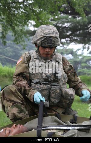 Spc. Jorge H. Garatecarabajo, ein mit Rädern versehener Fahrzeug Mechaniker 579 unterstützt Unternehmen, 6 Battalion, 37th Field Artillery Regiment, 210Th Field Artillery Brigade, 2 Infanterie Division/ROK-US kombinierte Geschäftsbereich zugeordnet sind, sichert ein Patient in einem Skedco im Camp Casey, Südkorea, 21. Juli 2017. Im Rahmen der Bekämpfung der Lebensretter Kurs, Soldaten gehandelt, realen Szenario, einen Unfall während einer Patrouille und ärztliche Hilfe. Stockfoto