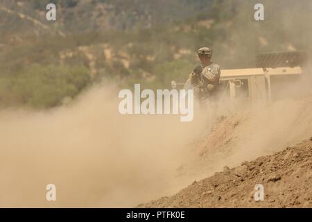 Us-Armee finden Sgt. John Brownlee, eine horizontale Bauingenieur an der 718th Engineer Company, zugewiesen in Fort Benning, Ga, in eine Wolke von Rauch bedeckt ist, während die Überwachung der Operationen eine berm für einen Kraftstoff blivet zu verbessern, eine faltbare Behälter, Einlagerung während des Kampfes Support Training Übung 91-17-03, 18. Juli 2017, am Fort Hunter Liggett, Calif. ca. 5.000 Armee Finden und National Guard Kräfte in der Übung teilgenommen. Erste Armee über 65 Beobachter Trainer/Ausbilder ihre Armee finden Partner zu erweitern auf der 91 Abteilung Weiterbildung und Training t unterstützen Stockfoto