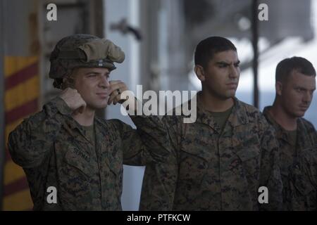 Us Marine Cpl. Erich J. Serwas, Links, einem truppführer mit Bataillon Landung Team 2 Bataillon, 6 Marine Regiment (BLT 2/6), 26 Marine Expeditionary Unit (MEU), zieht sich seine Kevlar Helm in Vorbereitung für schnelles Abseilen an Bord der USS Iwo Jima (LHD7) als Teil der Amphibischen Squadron - MEU Integration Training (PMINT), 14. Juli 2017. Der Zweck der PMINT wurde gemeinsame Aktionen zwischen dem 26. MEU und unterstützende Elemente in der Vorbereitung für den Einsatz der beiden US-Marine Matrosen und Marines zu führen. Stockfoto