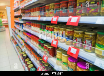 Verschwommenes Bild von Regalen mit Konserven im Supermarkt. Stockfoto