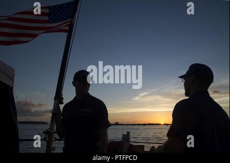 Coast Guard Seeleute Dakota Loiselle und Daniel Yacono verhalten Abend Farben auf der Coast Guard Cutter Tampa, Key West, Florida, 21. Juli 2017. Das Tampa, ist ein Medium endurance Cutter in Portsmouth, Virginia Küstenwache homeported Stockfoto