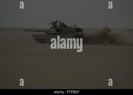 Eine M1A2 Abrams Kampfpanzer zu Alpha Company, 1.Bataillon, 12 Cavalry Regiment, 3. gepanzerte Brigade Combat Team, 1.Kavallerie Division Manöver durch die Udairi Bereich Komplex wie ein Teil von einem Angriff auf die gegnerischen Kräfte während Situationstraining übung des Unternehmens am 15. Juli 2017 zugewiesen. Die STX wurde verwendet, um die Einheit durch die Mission wesentliche Aufgaben zur Validierung der Bereitschaft der kombinierten Waffen Bataillone zu unterstützen. Stockfoto