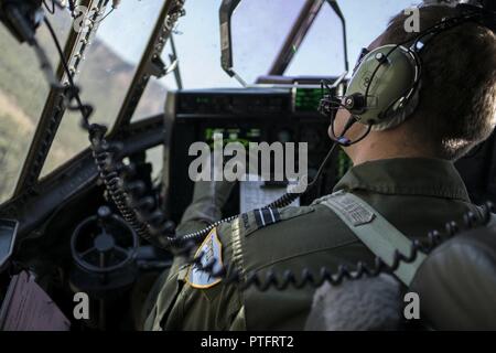 Ein Nr. 37 Squadron der Royal Australian Air Force Pilot schaut aus dem Fenster eines RAAF C-130J Hercules während einer ungleichen Formationsflug mit der US Air Force 17 Special Operations Squadron MC-130J Commando II Juli 12, 2017 in Queensland, Australien. Talisman Sabre 2017 bot die Möglichkeit, an der Weiterentwicklung der Interoperabilität mit Kollegen aus der RAAF durch tägliche Airborne operations low-level Bildung arbeiten, leiten die Luftbetankung Punkt zu gehören, sowie Personal- und Cargo Fallschirmabwürfen. Stockfoto