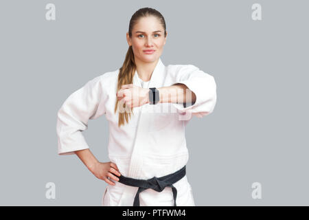 Schöne zufrieden Stolz blonde Junge athletische Frau posiert und zeigt Ihre smart Watch, lächeln und Kamera. Frau mit Fitness Armband. Ich Stockfoto