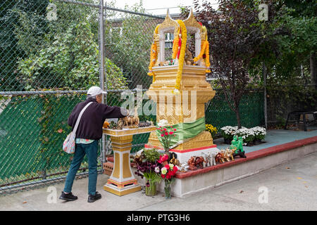 Eine ältere Thai Frau lichter Räuchern als Opfergabe an Buddah Buddah außerhalb des Wat Thai Thavorn Vanaram Tempel in Elmhurst, Queens, New York Stockfoto