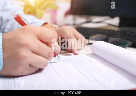 Man füllt Formular mit Pen. Bild von Gläsern und Tastatur. Stockfoto