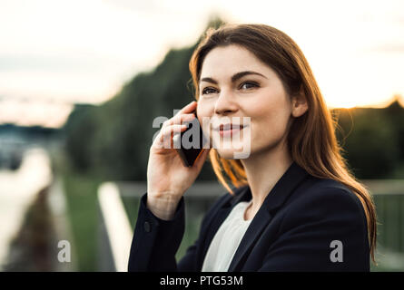 Eine junge geschäftsfrau mit Smartphone im Freien, ein Telefonanruf. Stockfoto