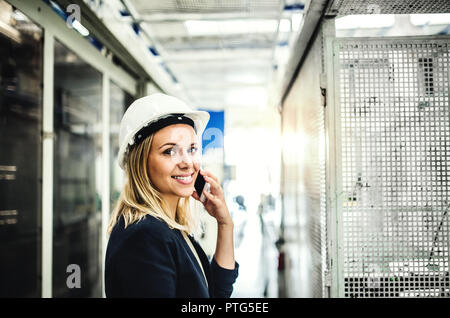 Ein Porträt einer Frau Techniker am Telefon, in einer Fabrik. Stockfoto