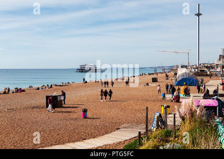 Brighton, England, 07. Oktober 2018. Menschen am langen Kiesstrand in Brighton, die British Airways ich 360 und West Pier auf dem Hintergrund ruiniert, Sel Stockfoto