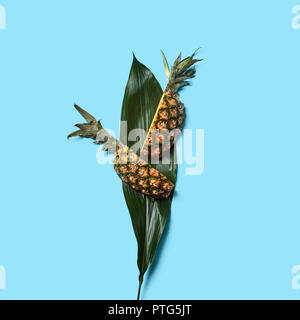 Grünes Blatt und Scheiben von Reif bio Ananas auf einem blauen Hintergrund mit Platz für Text. Flach Stockfoto