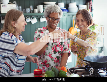 Active Senior Frauen Freunde kochen, rösten Cocktails in der Küche Stockfoto