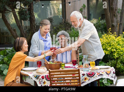 Active Senior Freunde genießen Rose Wein und Mittagessen an der Terrasse Tisch Stockfoto
