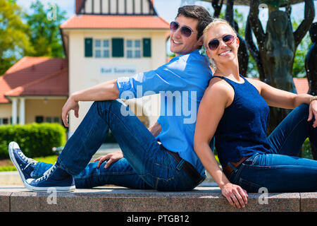 Lächelnd stilvolle junges Paar zurück zu zurück in der Nähe der Brunnen genießen. Stockfoto
