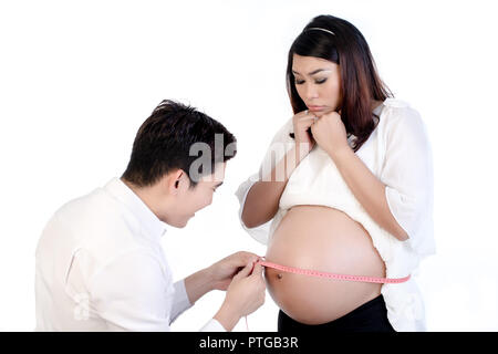 Lächelnd Mann seine schwangere Frau von Bauch mit Klebeband auf weißem Hintergrund Stockfoto