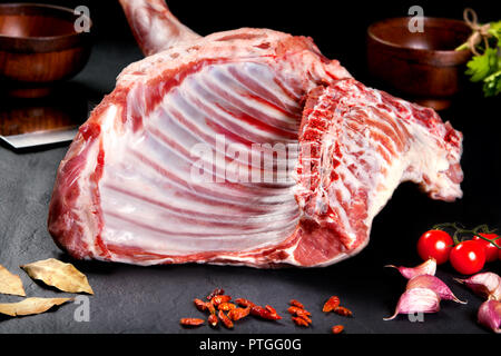 Frisch und rohes Fleisch. Fleisch Rippe und Koteletts für das Kochen auf schwarzem Hintergrund mit Tomaten Stockfoto