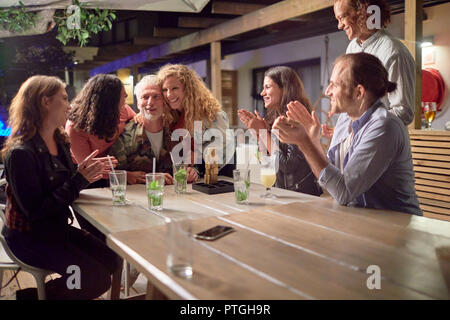 Gerne Freunde, Klatschen, Feiern auf der Terrasse bei Nacht Stockfoto