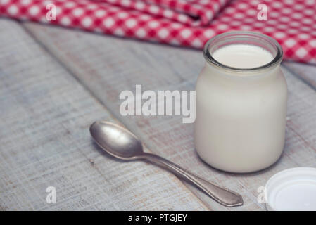 Lecker und gesund weißen hausgemachte Joghurt in Gläsern auf einem weißen Holztisch. Bereit, wie diese zu essen, oder das Hinzufügen von Obst, Getreide oder Nüsse. Stockfoto