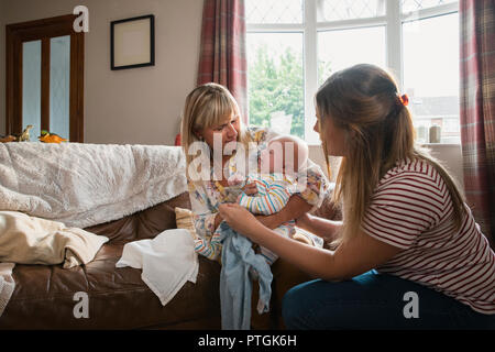 Mitte nach Mutter zu Hause ist, mit ihrem Baby Sohn. Seine Großmutter besucht und hilft, das Baby, wie er weint. Stockfoto