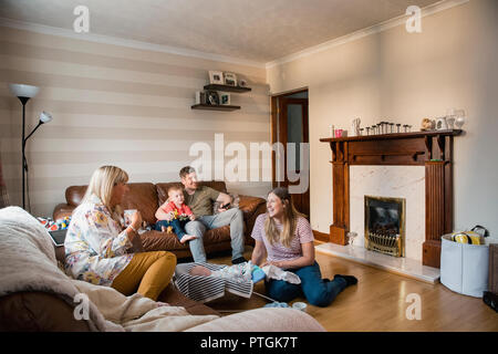 Junge Familie zu Hause mit Ihrem Sohn und neugeborenes Baby und die Großmutter ist, Sie besuchen für Tee. Stockfoto