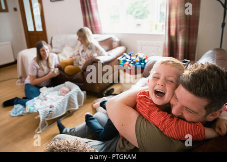 Familie mit zwei Kindern und ihre Großmutter sitzt im Wohnzimmer auf den Sofas. Sie sind entspannend, Fernsehen und sprechen. Die Großmutter ha Stockfoto