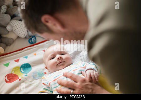Mitte - Erwachsene Vater überprüfung oben auf sein neugeborenes Baby Boy, während er in der Krippe liegt. Stockfoto