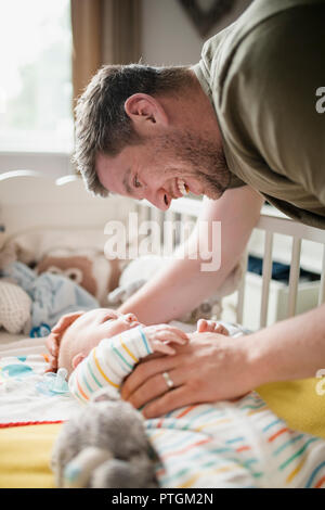 Mitte - Erwachsene Vater überprüfung oben auf sein neugeborenes Baby Boy, während er in der Krippe liegt. Stockfoto