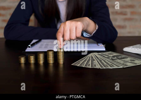 Geschäftsfrau picks Münzen auf den Tisch und zählt Geld. Geschäftskonzept. Stockfoto