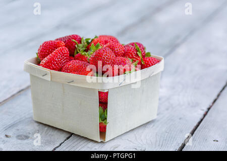 Box von frisch gepflückten reifen roten Erdbeeren auf einem Holztisch. Stockfoto