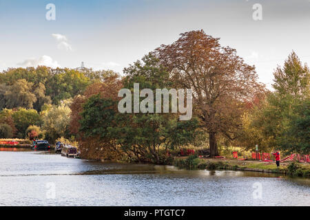 Ein angler in der Nähe von Iffley Lock auf der Themse in rot gekleidet, die harmonisch in die roten Wanderweg Barrieren und Baum Farben, Oxford, Stockfoto