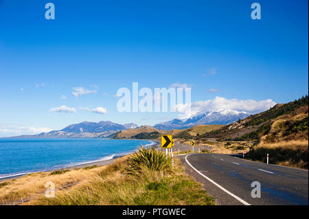 State Highway 1, iconic Küstenstraße in der Nähe von Kaikoura, Neuseeland, einer der oberen Küstenstraßen der Welt. Verschneite Berge treffen Himmel, Meer und Straße Stockfoto