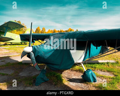 Blick auf klassische Flugzeug auf dem grasbewachsenen Flugplatz; Flugzeuge nach dem Flug mit Fällen auf Propeller und andere Elemente; Freizeit und Unterhaltung Stockfoto