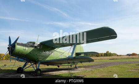 Blick auf klassische Flugzeug auf dem grasbewachsenen Flugplatz; Flugzeuge nach dem Flug mit Fällen auf Propeller und andere Elemente; Grün militärische Flugzeuge, die auf dem Stockfoto