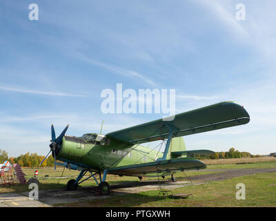 Blick auf klassische Flugzeug auf dem grasbewachsenen Flugplatz; Flugzeuge nach dem Flug mit Fällen auf Propeller und andere Elemente; Grün militärische Flugzeuge, die auf dem Stockfoto